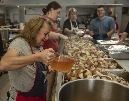 Granger Mayor Monica Stojanik, a church member, helps prepare potatoes for serving plates.