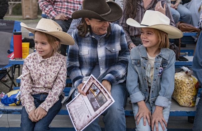 Geeg Surgi, center, spends time with her granddaughters Violet Gulbranson, 7, left, and Avery Gulbranson, 9, right, as they watch the girls' older sister Clara Gulbranson  compete in Barrel Racing and Polebending.