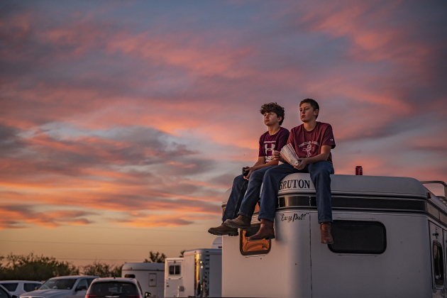 Friends Will Broadway, left, and Holt James, right, both 13, watch the action from atop a horse trailer as evening skies fill with color.