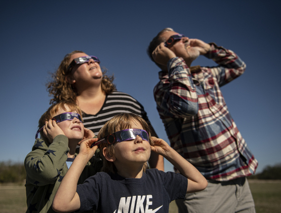 5-year-old Luca Kealy, front, and his brother Oliver, 7, watch the annular eclipse with their grandparents Dean and AnDee Flohr during a Saturday, October 14, 2023 gathering at Berry Springs Parks & Preserve,  hosted by Friends of Berry Springs Park.  An annular eclipse occurs when the moon gets between the earth and sun.  The eclipse's visibility was approximately 89% in the Austin area. 