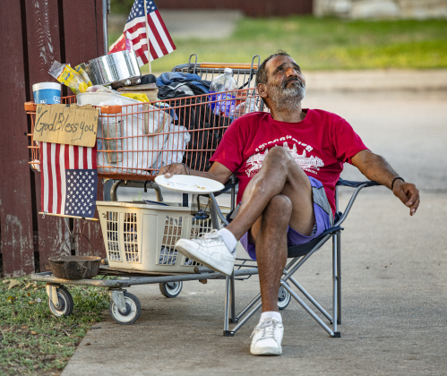 Daniel Ruiz, who says he's been homeless most of his life, relaxes after enjoying a free  meal of burgers, hot dogs and tamales during a National Night Out event held at Stonehaven Apartments. Ruiz, from San Antonio, was headed for the Dallas area.