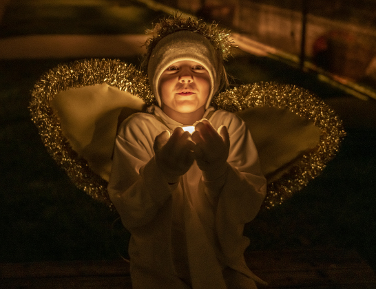 6-year-old Grace Smurthwaite holds a light up to her angel's face while waiting to join other angels in a manger scene at  Immanuel Lutheran Church for their Pilgrimage to Bethlehem, the church''s Live Nativity, on Saturday, December 9, 2023.