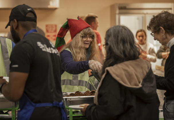 Sun City Rotary Club President Debbie Ballou (in festive hat at center) helped dish up breakfast items for attendees.
