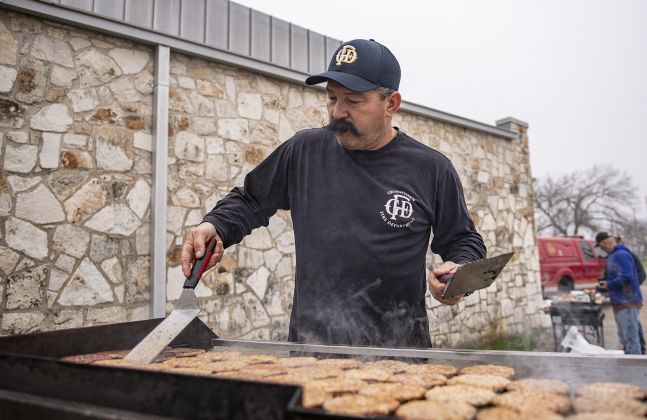 Clayton Holder, a member of the Georgetown Fire Department, helps prepare breakfast sausage.