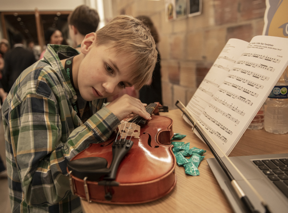 Annie Purl Elementary 5th grader Auburn Pyka, 11,  a member of the school's Strings program, tunes his violin during the Georgetown Independent School District State of the District event held at GISD headquarters on Thursday, February 15, 2024.    Photo by Andy Sharp.  
