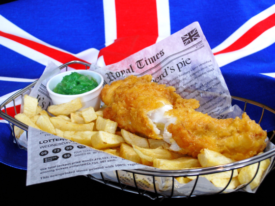 A basket of fish and chips with mushy peas.