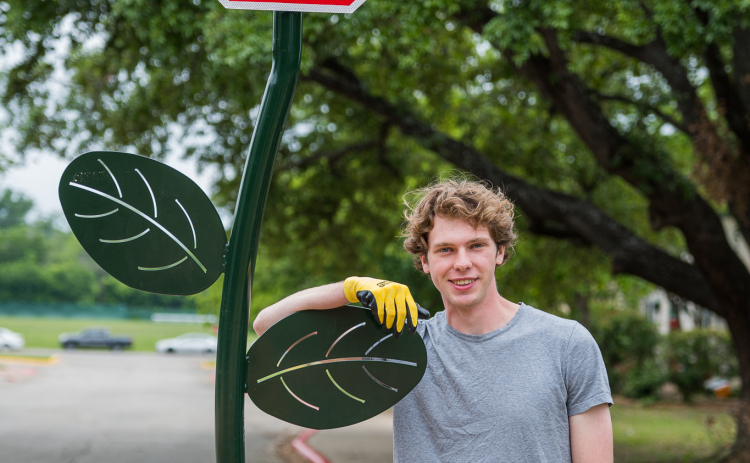 Southwestern University senior Ashton Frey stands next to one of three “Red Poppy Stoppy signs” installed on campus. The signs are the result of Mr. Frey’s efforts through the Houston Art & Paint Initiative, a nonprofit he started. Photo by Brigid Cooley