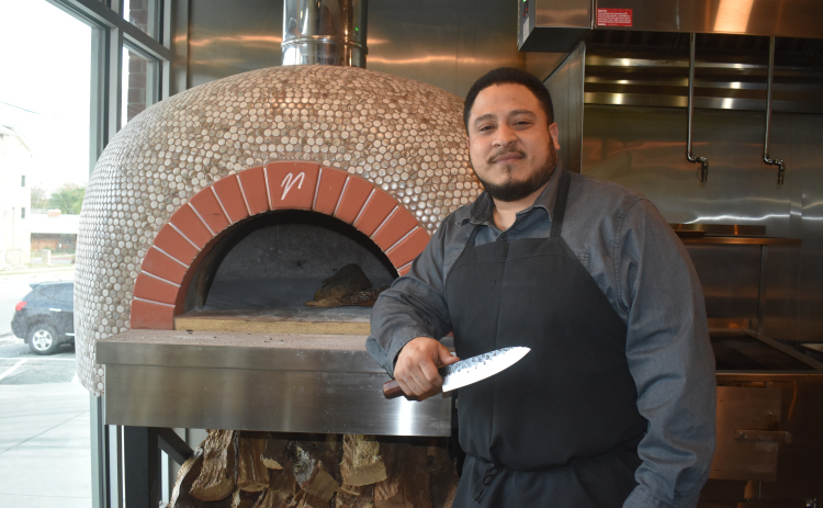 La Riv Executive Chef Johnny Pincay, with his favorite chef’s knife, at the restaurant’s wood-fired pizza oven. The oven uses three cords of wood weekly.