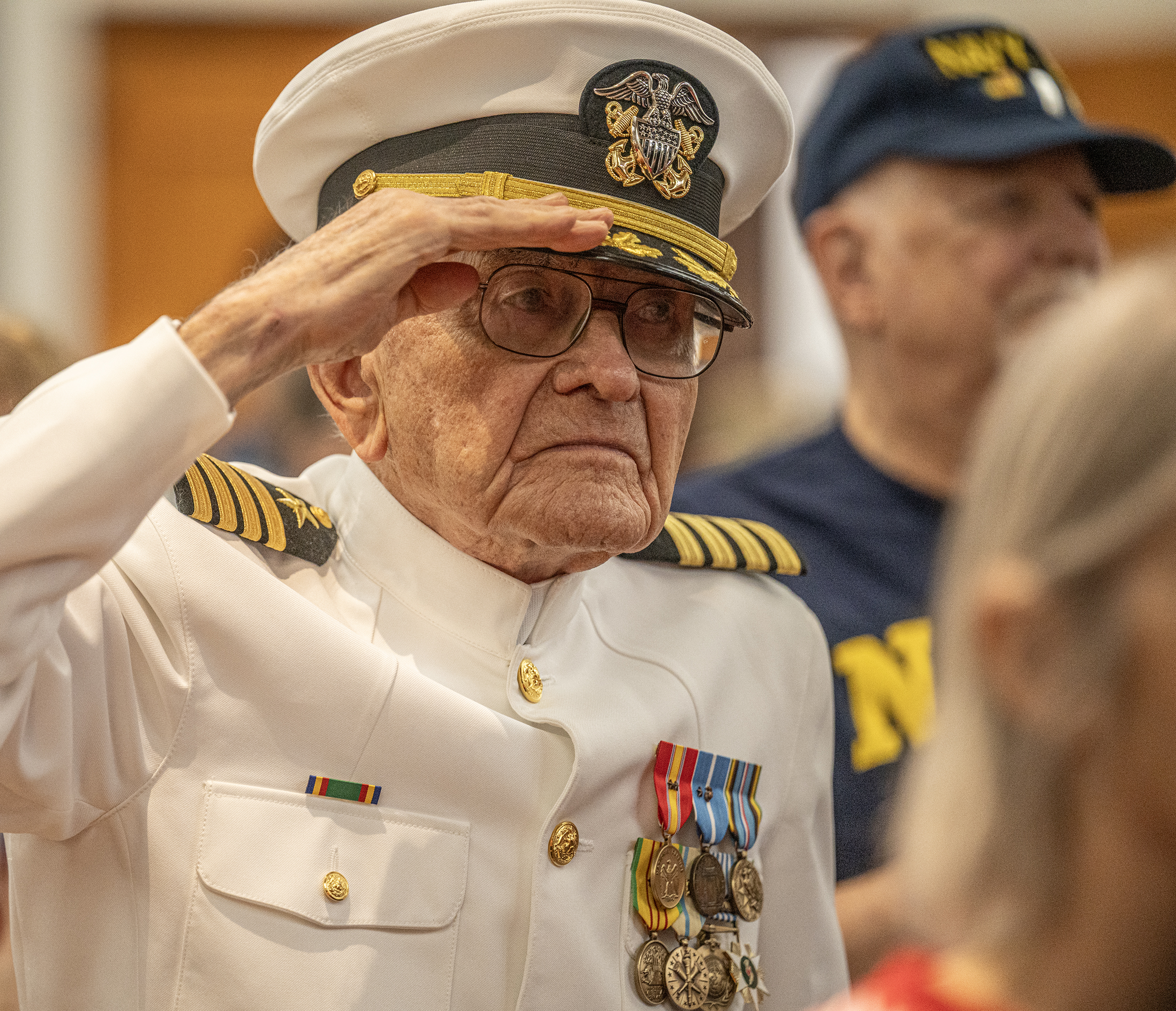 Navy Veteran Sylvester Shelton, 97, who retired as a Captain, salutes during the playing of the National Anthem during the Memorial Day ceremony held in Sun City on Monday, May 25, 2026.  The chance of rain moved this year’s ceremony inside the Sun City Social Center ballroom, filled to capacity with several hundred attendees.    Photo by Andy Sharp.