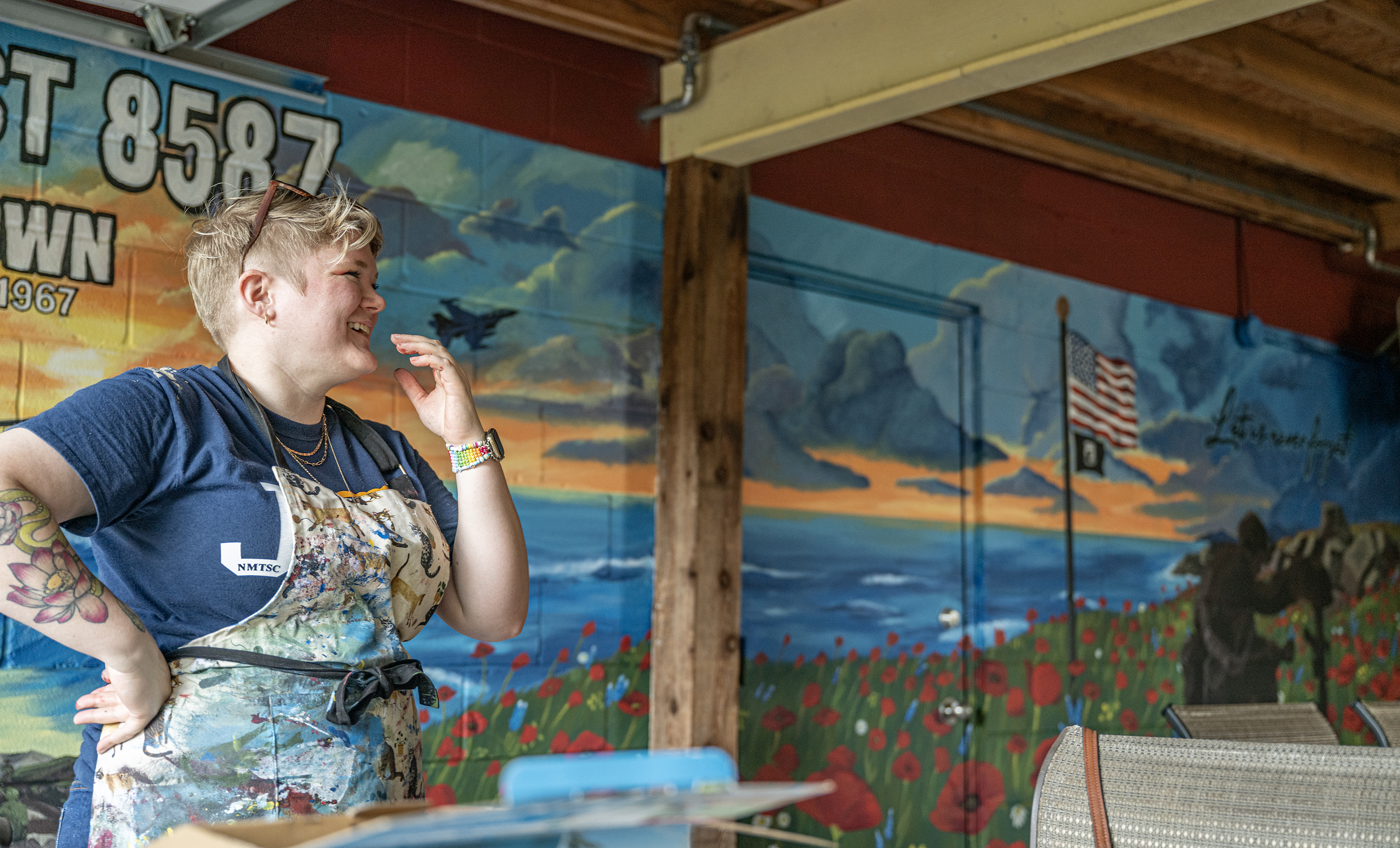 Artist Shelby Gage smiles  Friday, August 14, while she puts finishing touches on a VFW mural she created for Msg. Ben D. Snowden Post 8587. Last steps included adding a clear coat to protect her work.