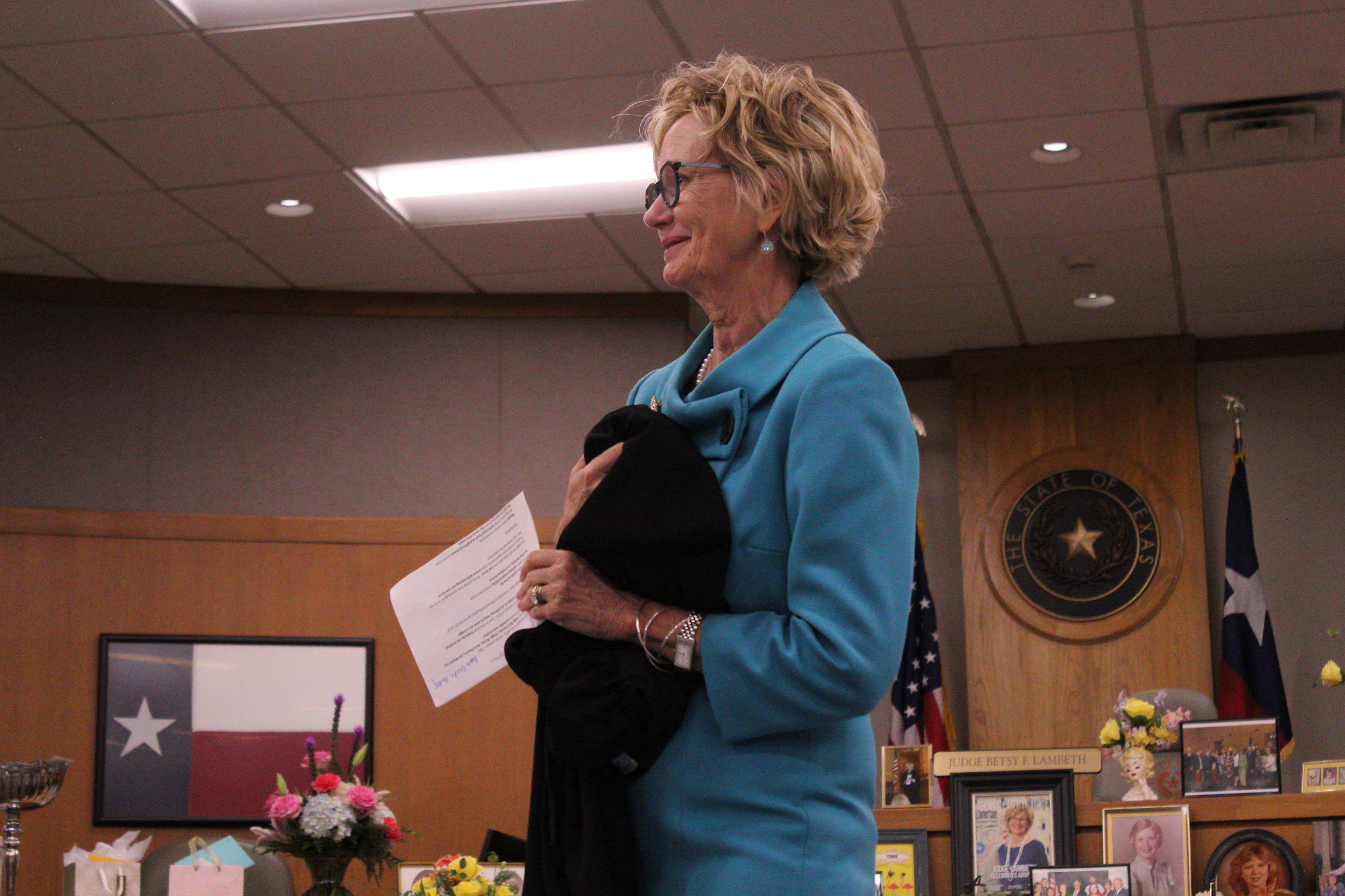 Judge Betsy Figer Lambeth of the 425th District Court clutches a Judges robe as she gives a speech at her retirement ceremony in the 277th District Courtroom on August 21. Her mother made the robe for Judge Lambeth’s swearing in ceremony on January 1, 2013. Photo by Nalani Nuylan.