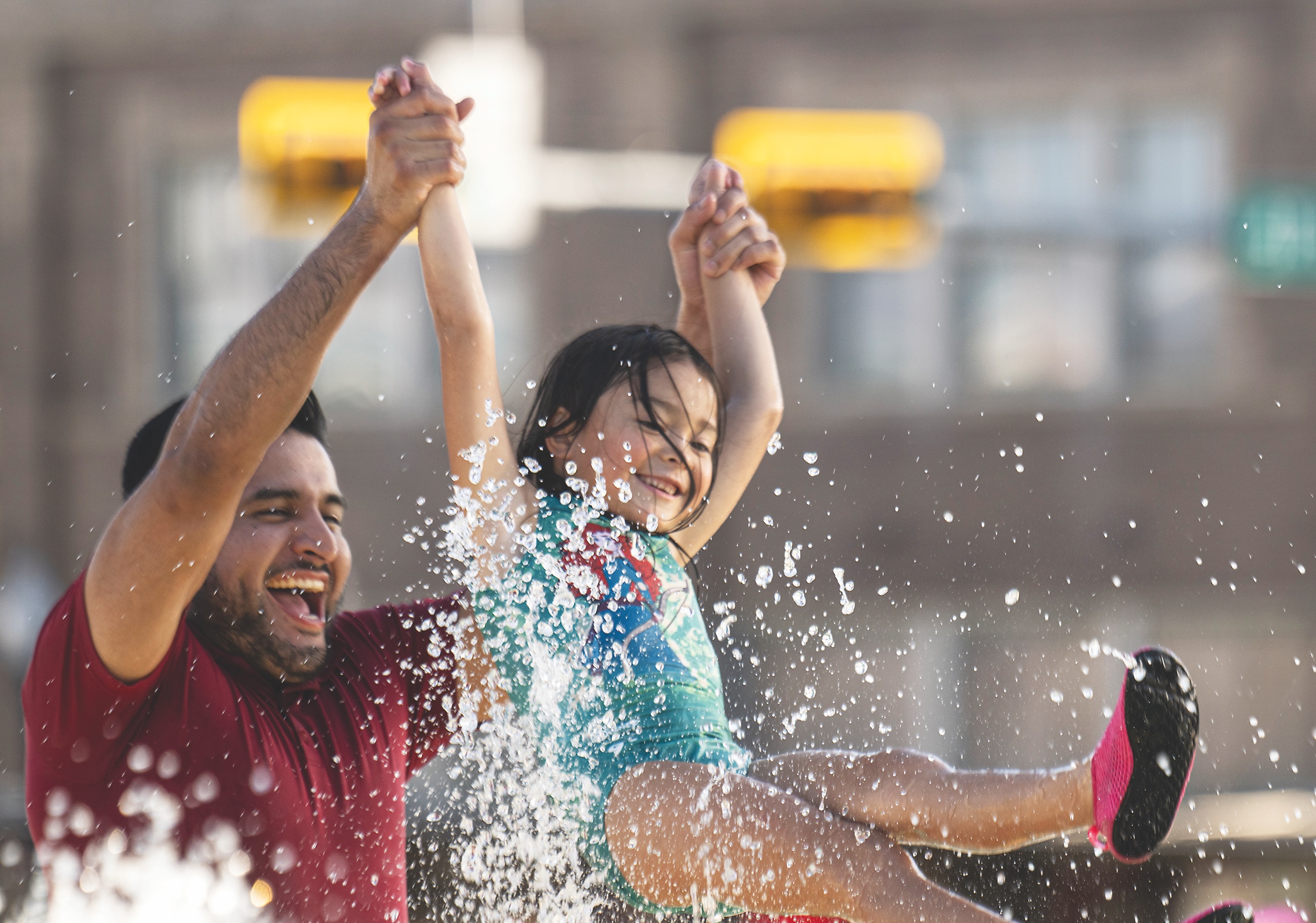 Jose Rogel swings his daughter Luna, 5, through the water during a visit to the splash pad at Heritage Square Park on Tuesday, June 17, 2025. 