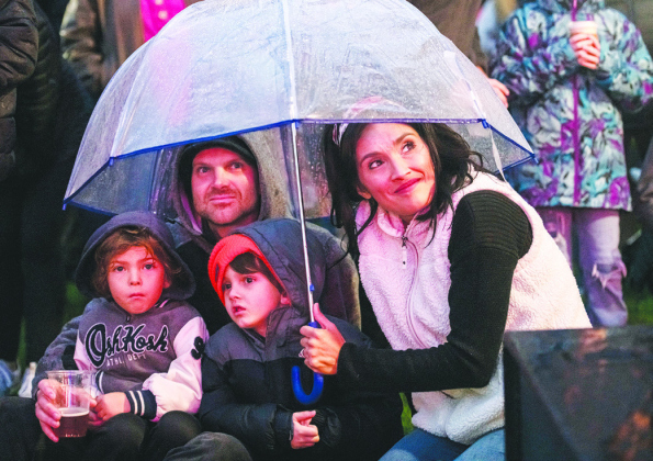 Chase and Erica Wessel huddle under an umbrella with their children Ryder, 4, and Zane, 5.