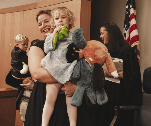 Judge Brandy Hallford, right, congratulates the Banks family, including mom Emily Banks, front, with Lexeigh Olivia Banks, 3, and her brother Koa Banks, 2, with dad Josh Banks.