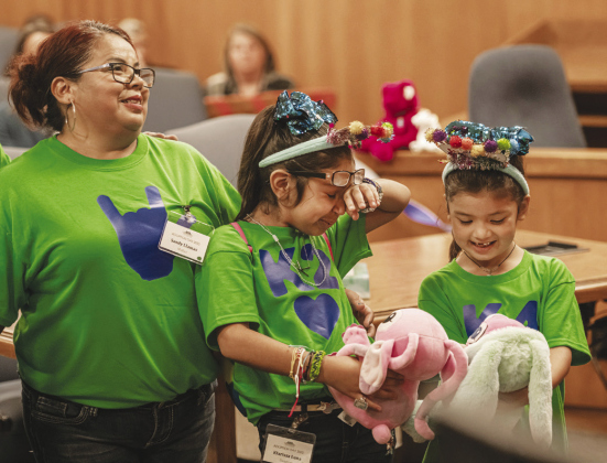 Klarissa Luna, 8, wipes away a tear as she stands with her sister Karol, 7, and their new mom, Sandy Llamas. Also adopted by Sandy were daughter Karol Luna, 7, and son Kurt Luna 12. Sandy’s fiancé Jeff Richmond was also present for the adoption.