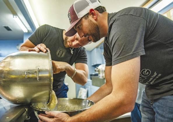 Kyle Janke, left, and Michael Thornton team up to transfer just-made dough to a tub where it will rise for several minutes.