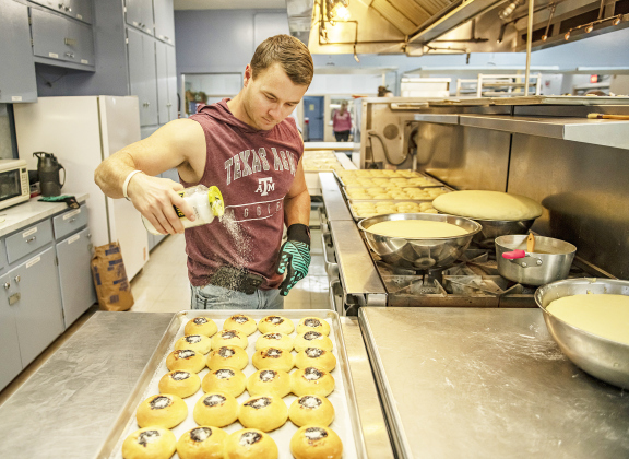 Right, Zach Strmiska adds a sprinkling of sugar to the tops of just-baked kolaches.