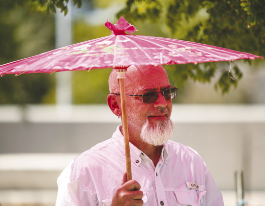 Michael Price uses his parasol to keep the afternoon sunlight in check during Fiesta Georgetown.