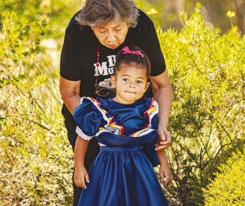 Above, Guitarist Rogelio Urive performs with Mariachi Guadalajara. Right, Lucila Chavarin, 2, gets her dress adjusted by longtime family friend Juanita Pedraza as they watch Round Rock Ballet Folklorico perform. Lucila’s dress was made for her by Pedraza, whose daughter Marisol Pedraza is a member of the troupe. When Lucila turns three in a few weeks, she’ll be eligible to join the troupe, but for now enjoys dressing the part.