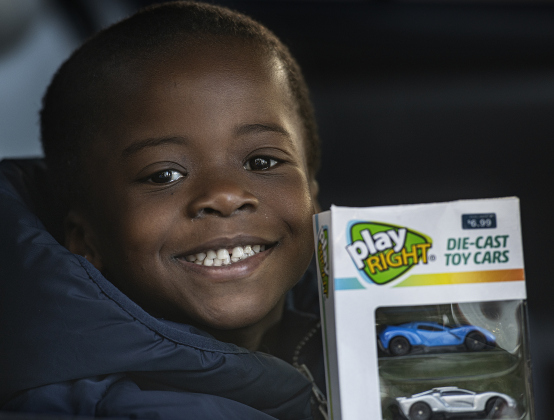Jullian Moye, 5, had a big smile while holding onto a bonus gift handed to him while waiting in line for his family's gift boxes during the Georgetown Police Department's Blue Santa distribution at the Georgetown Public Safety headquarters December 17, 2022. Volunteers gave out gift boxes for 2,235 children and over 700 pre-qualified families this year.