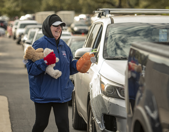 Mary Egleston, a volunteer with the Citizen's Police Academy Alumni Association, hands out stuffed animals to cars waiting in line for their main gift boxes.