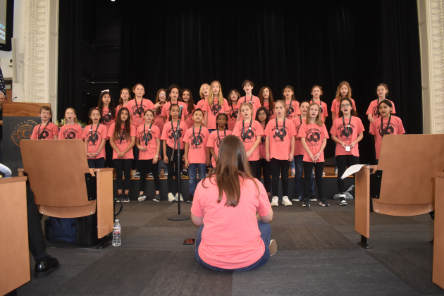 Williams Elementary School music teacher Hannah Mize conducts the school’s honor choir at the State of the District event.