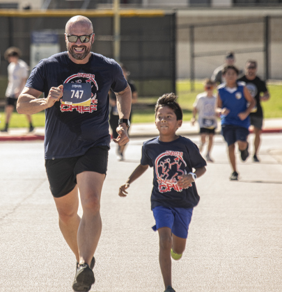 Georgetown Police Chief Cory Tchida, left, is joined by 8-year-old Ellison Shotwell as they near the finish line for their 5-K Race during Chase the Chief.