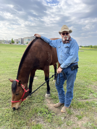 Mark Dial, equine manager at ROCK, lets Grant the horse graze nearby while waiting for the event to start.