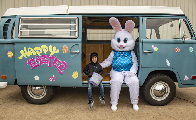Ezra Gomez, 5, poses with the Easter Bunny by a 1970 VW bus owned by church member Clark Underwood.
