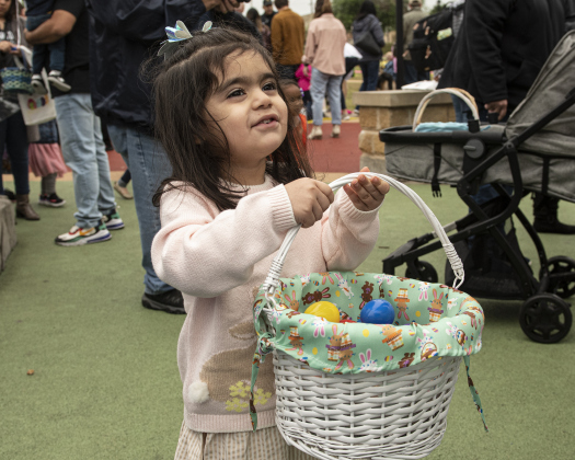 Kai Ruiz, 2, holds onto her basket of collected eggs.