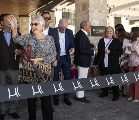 Elaine Davenport, who moved into The Hacienda at Georgetown as its first resident in April 2021, waves as she prepares to cut the ribbon marking the community’s grand opening on Saturday, April 15.