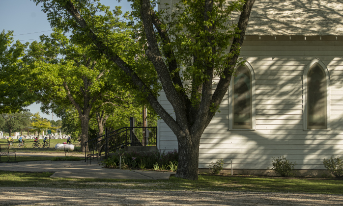 Cyclists make their way along F.M. 1105 as they pass near St. Peter Lutheran Church in Walburg.