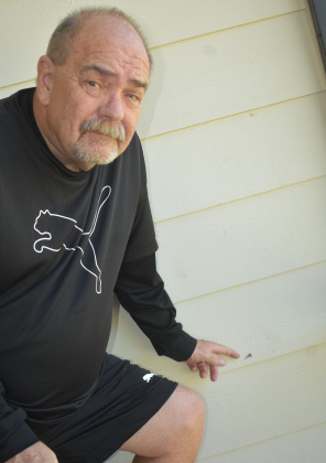 Sun City homeowner Kirk Kelley points to the hole in his porch wall made by a bullet of unknown origin. Photo by Katherine Anthony