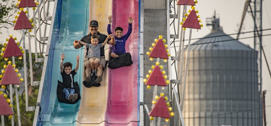 Bryan Perez takes a fast ride on Fun Slide with his children, including (left to right) Damian, 6, Noah, 3 (in dad's lap) and Alorik, 8, on Thursday, May 11, 2023, the opening night of Lakefest in downtown Granger. 