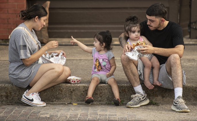 Elizabeth Gonzales, left, and her husband Xavier Gonzales, right, have an evening snack along West Davilla Street with their kids, including Madelynn, 2, center, and Mariana, 18-months-old, with dad, during the second night of Granger's Lakefest on Friday, May 12, 2023.