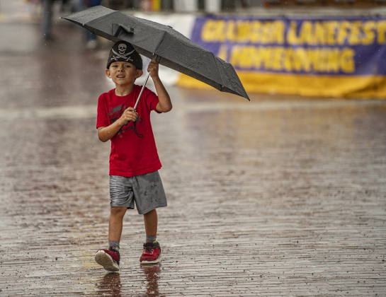 5-year-old Lucan Gehrke does his best to stay dry on the wet pavement of  West Davilla Street  on Saturday, May 13, 2023, the  third and final day of Granger's Lakefest.