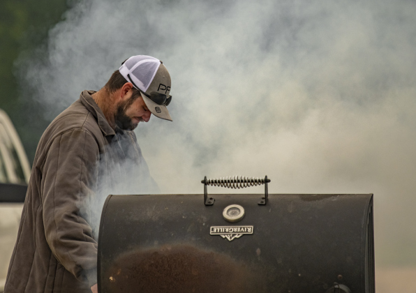 Josh Vrana, whose barbecue cook-off team is Sausage King, is surrounded by smoke as he checks on the progress of his team's seafood entry  on Saturday, May 13, 2023.