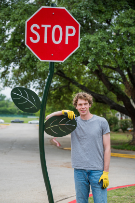 Southwestern University senior Ashton Frey stands next to one of three “Red Poppy Stoppy signs” installed on campus. The signs are the result of Mr. Frey’s efforts through the Houston Art &amp; Paint Initiative, a nonprofit he started. Photo by Brigid Cooley