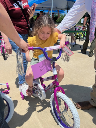 Pre-K student Karter Ayers gets on her new bike in the parking lot of Purl Elementary School on Thursday, May 18. Photo by Abbey Archer