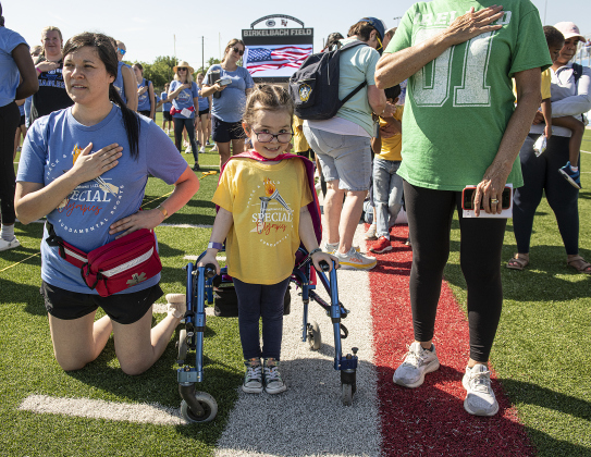 5-year-old Tessa Trimble, a Wolf Ranch Elementary student, center, is pictured with teacher Evelyn Felts, left,  as the crowd salutes during the opening ceremonies.