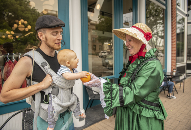  Liz Carbrey Weaver, in her role as Margaret Corinna Henderson Taylor (the wife of Emzy Taylor) is shown  at 7th Street and Austin Avenue on Saturday, May 20, 2023  as she visits with Jeff Stump and his 6-month-old son Azure.