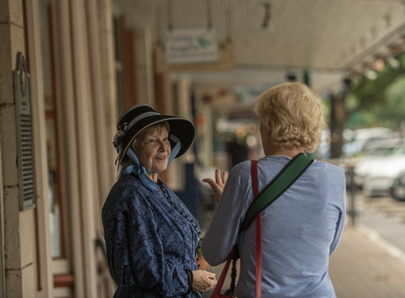 Docent Denise Haverty, left, in her role as Asenath Davis Clamp, visits with Georgene Richaud along Main Street.  Asenath Clamp was married to Christian Augustus Daniel Clamp, who was born in Prussia, moved to Texas in 1846, then to Georgetown in 1851.  He was a successful carpenter, cabinet maker and developer  in the area.   Clamp owned a furniture store on Main Street..