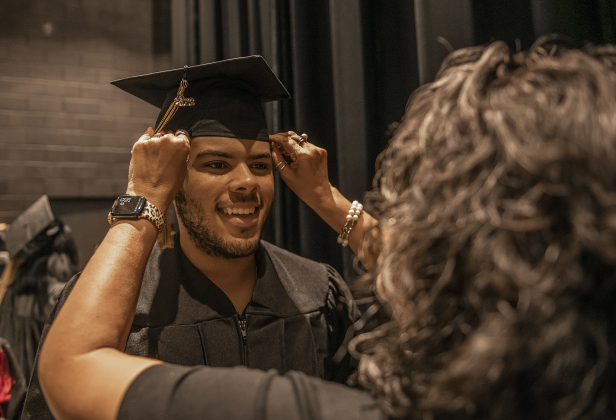 Richarte High School graduating senior Dylan Reyes gets help from Richarte staffer Barbara Barrett before the start of the commencement ceremony.