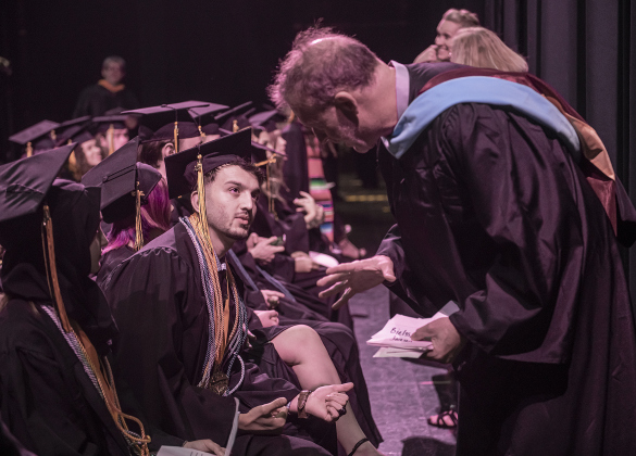 Richarte High School principal Rob Dyer, right, goes over program details with Richarte Valedictorian Walid Azizi, center, and Salutatorian Marwa Azizi, Walid's sister, before the start of the commencement ceremony.