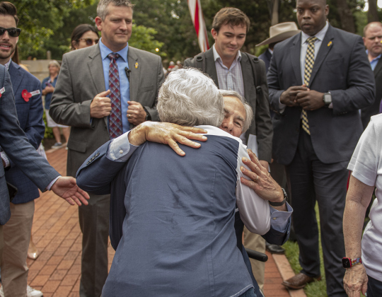 Texas Governor Greg Abbott gets a hug from Betty Schleder  at the Sun City Texas Community Association Memorial Day observance,  held Monday, May 29 at the Georgetown-Williamson County Veterans Memorial Plaza in Sun City.