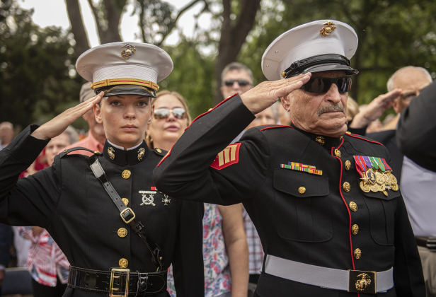 U.S. Marine Corps  active duty member Penny Pellegrini, left, is joined by her father, retired U.S. Marine Corps member Dennis Pelligrini,  as they offer salutes during the playing of the National Anthem during the Sun City Texas Community Association Memorial Day observance