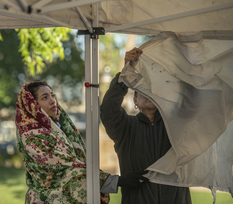 Monique Shidell is wrapped in a blanket to lessen the cold and wind as she helps her grandmother Mai Shidell set up a vendors' booth for Mai's Crafts along Main Street during the Red Poppy Festival on Saturday, April 29, 2023.  Although the wind remained throughout the day, temperatures rose from the lower 50s into the lower 70s.