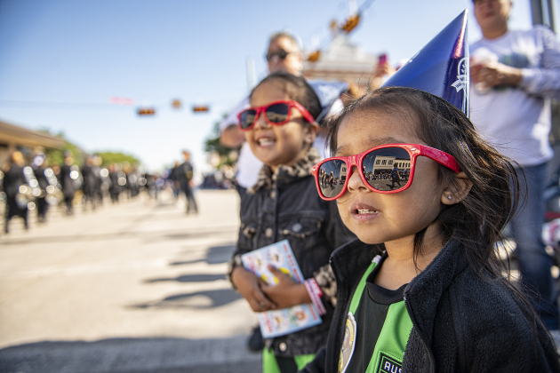 Viviana Sanchez, 2, front, and her sister Jasmin, 4, at back left, watch the parade along Austin Avenue, waiting to see their cousin, Georgetown High band member Aiden Wells, a trumpet player,  pass by them during the Red Poppy Festival.