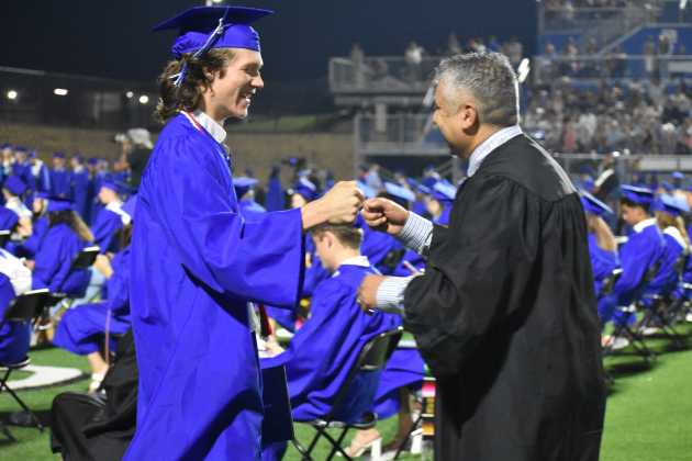 Wyatt Ewing fist bumps with faculty member Ramiro Luna.
