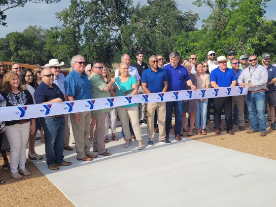 Williamson County Commissioner Cynthia Long, center teal, and The YMCA of Central Texas at Twin Lakes Park cut the ribbon to open a new pedestrian bridge. Photo by Nalani Nuylan